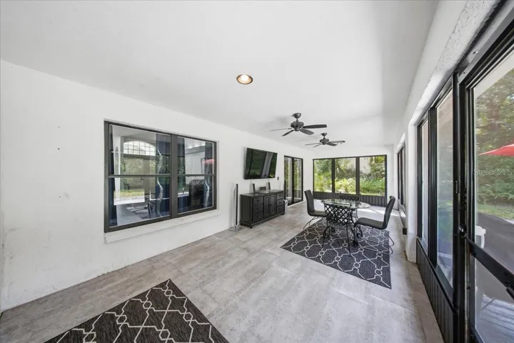Expansive screened lanai, enhanced with ceramic tile flooring and 65" wall-mounted television.