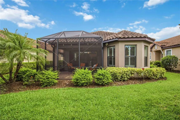 Back of home with lush landscaping