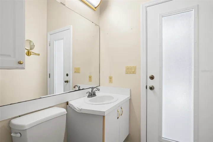 The third bath features a mirrored vanity, storage cabinetry, and direct access to the screened lanai.