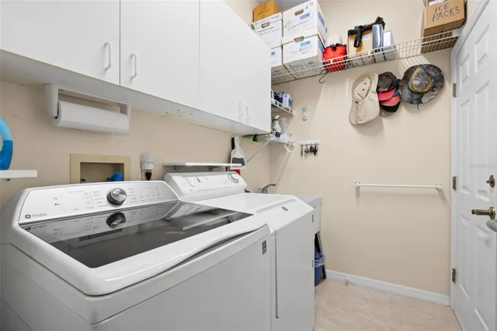 Ample cabinetry, overhead storage, and a utility sink enhance the functionality of the laundry room.