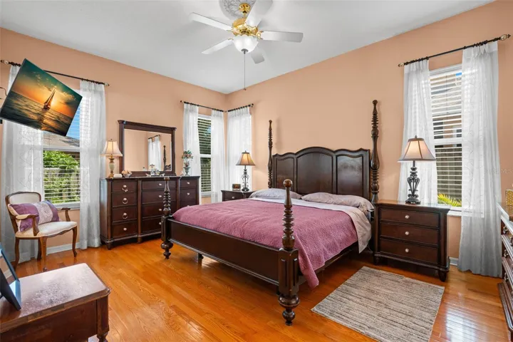 Multiple windows fill the primary bedroom with natural light, enhancing its bright and airy feel.