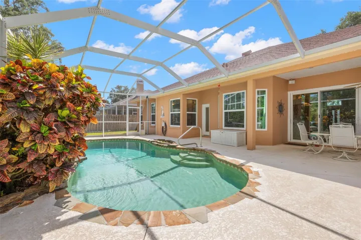 The screened pool is complemented by generous deck space, a covered lanai, and lush tropical landscaping.