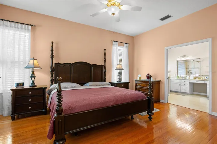 The primary bedroom features hardwood flooring, high ceilings, and direct access to the en-suite bath.