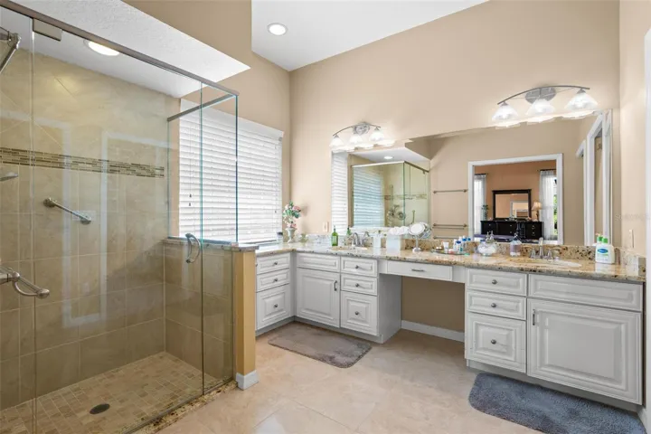The en-suite bath features dual vanities, granite countertops, a dedicated makeup station, and a spacious walk-in shower.