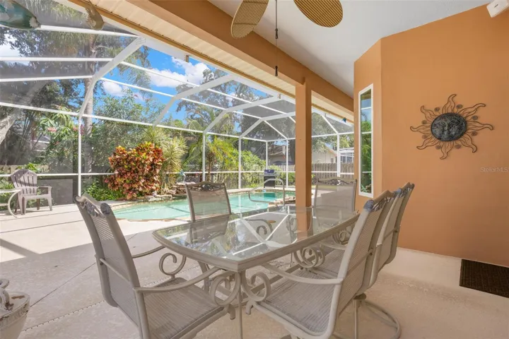 The covered lanai provides a comfortable setting for outdoor dining and relaxation overlooking the screened pool.