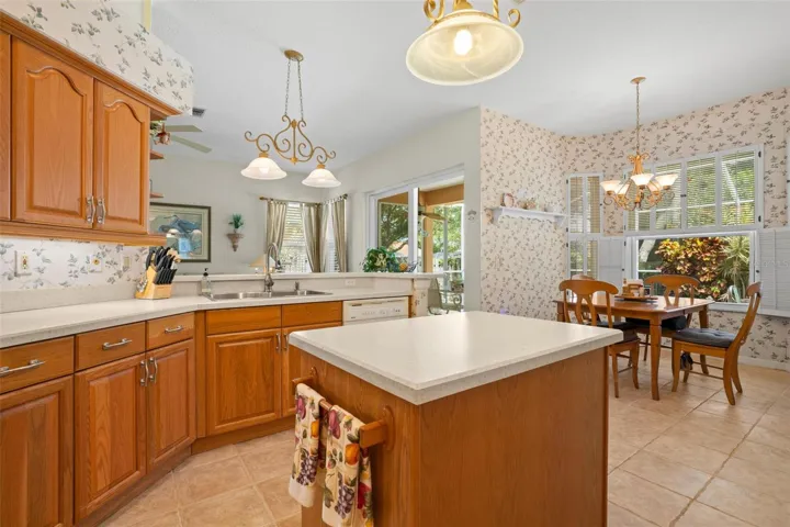 The kitchen features a center island, generous cabinetry, and a bright breakfast nook with views of the lanai.