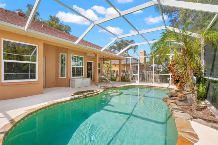 The screened pool features natural stone accents and is thoughtfully integrated with the home's covered lanai and outdoor living spaces.