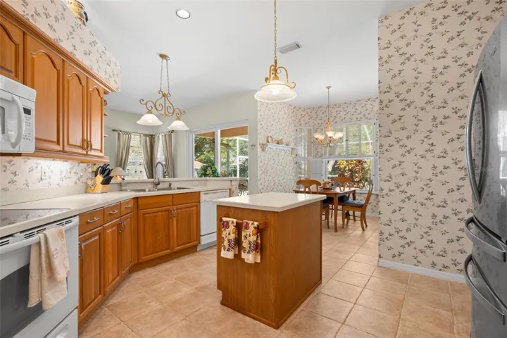 The kitchen features a center island, abundant cabinetry, and a sunny breakfast nook overlooking the lanai.