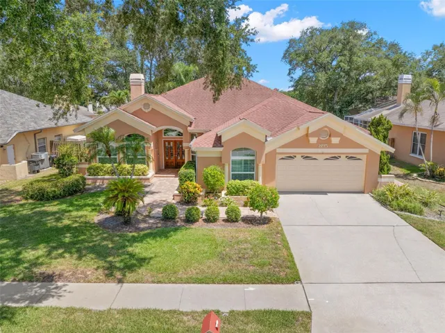 Mature trees and established landscaping frame the home, while the two-car garage and extended driveway provide everyday convenience.