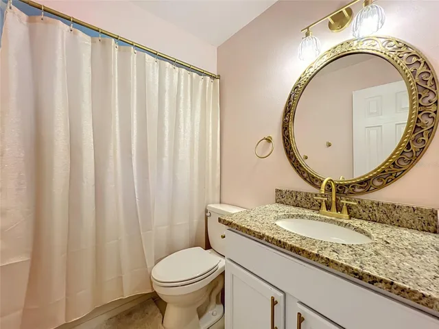 Guest bathroom with tub/shower combo and granite countertop.