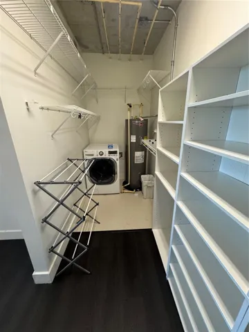 walk-in closet with shelves and washer/dryer unit