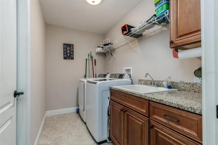 Inside laundry with sink, shelving and cabinets