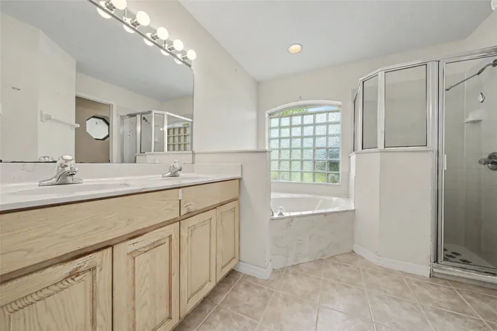 Primary bathroom with double sink vanity and separate shower and separate tub and commode room