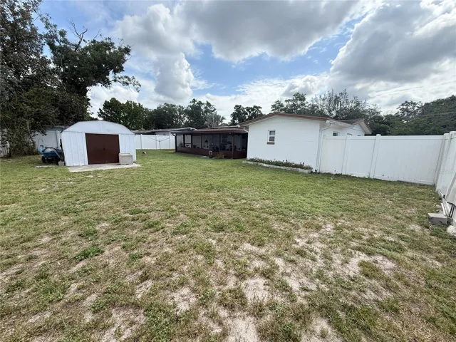 backyard with shed and screen enclosed patio, fully fenced yard