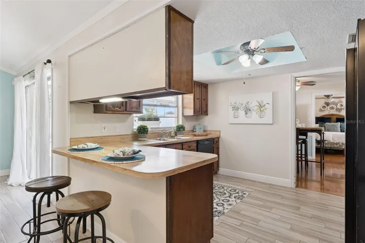 The kitchen has solid wood cabinets, black appliances, breakfast bar and a window at the kitchen sink that overlooks the lanai and pool. There is even a ceiling fan in the kitchen! From the kitchen you can see into the dining room and master bedroom.