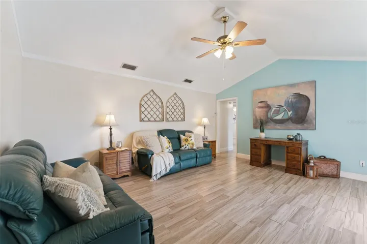 Large family room with ceiling fan and sliding glass doors that lead you to the covered lanai that overlooks the pool