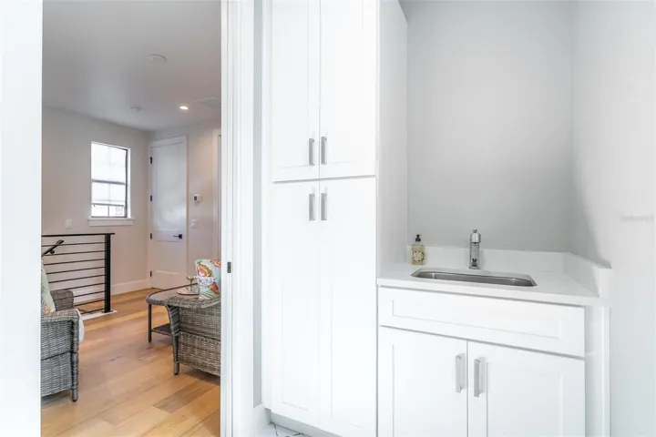 Upstairs laundry room has a sink and additional storage.