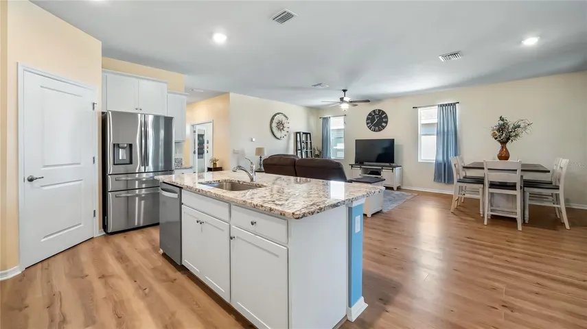 The kitchen is equipped with stainless steel appliances, granite countertops, and a breakfast bar overlooking the living room and dining room.