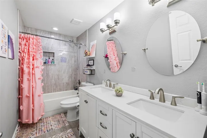 Beautifully updated secondary bathroom with quartz counters, dual sinks, and designer tile work