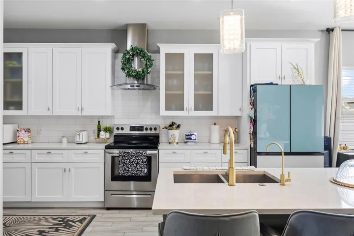 Fully renovated kitchen featuring quartz countertops, white shaker cabinets, stainless steel appliances, and oversized island seating