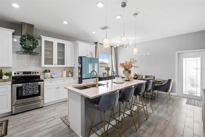 Fully renovated kitchen featuring quartz countertops, white shaker cabinets, stainless steel appliances, and oversized island seating