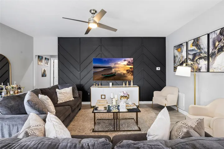 Spacious open-concept living room with designer accent wall and seamless flow to the kitchen and dining areas.