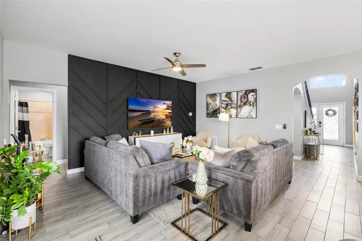 Spacious open-concept living room with designer accent wall and seamless flow to the kitchen and dining areas.