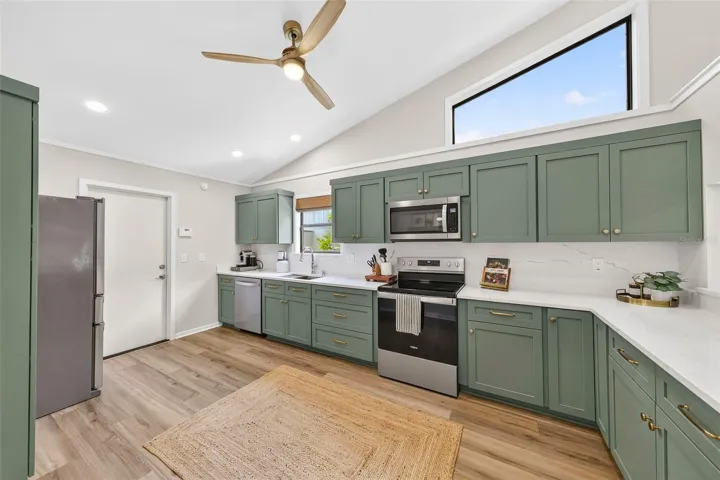 New Kitchen with custom sage cabinetry with quartz counters and backsplash