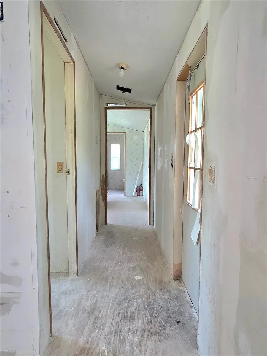 The hallway leads to the first bedroom on the left, the primary suite is located at the back of the home, and the door to the backyard is on the right.