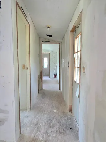 The hallway leads to the first bedroom on the left, the primary suite is located at the back of the home, and the door to the backyard is on the right.