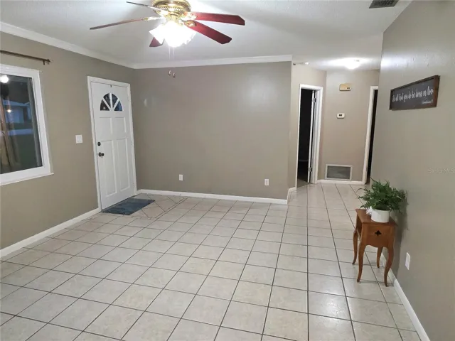 Another view of the living room showing front door and going into the bedroom area