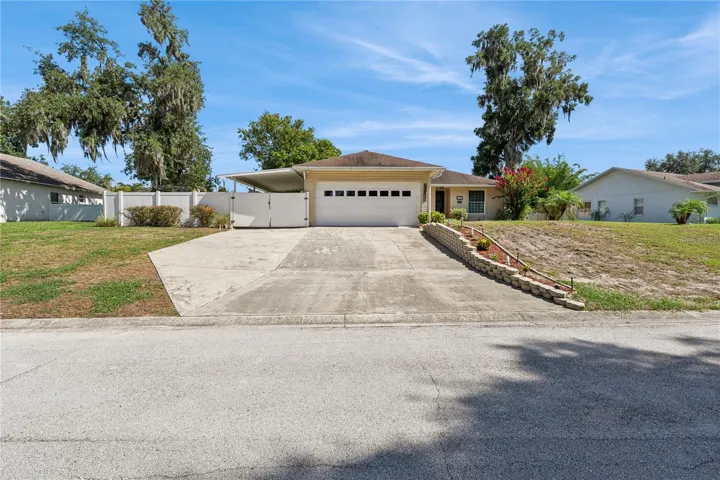 Front of home with HUGE driveway and gates and carport for boat / rv storage