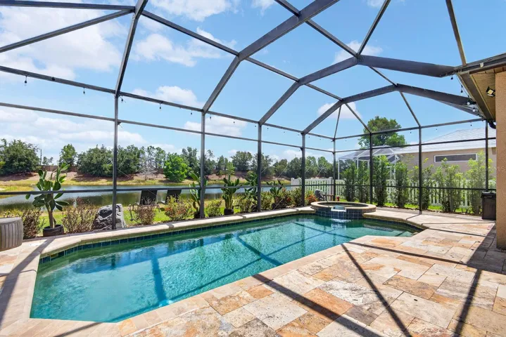 Beautiful pool and spa with lake and trees in back