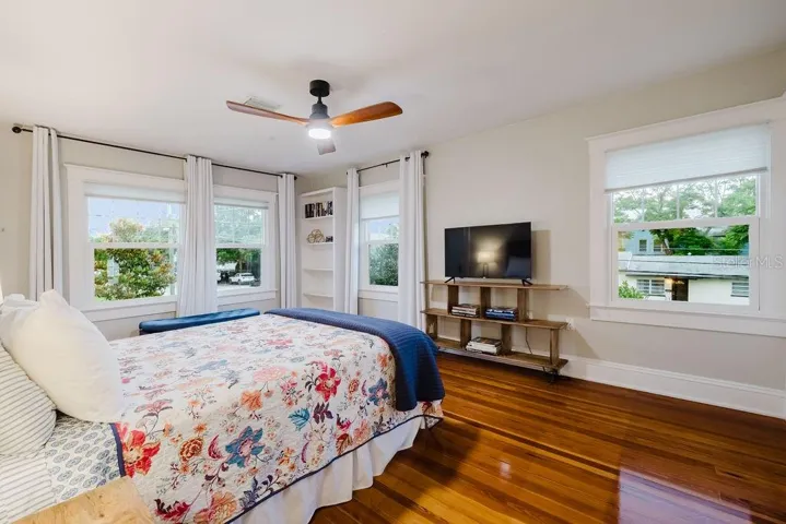 Primary bedroom on second floor with built in shelving and light and bright windows. Beautifully restored heart pine flooring.
