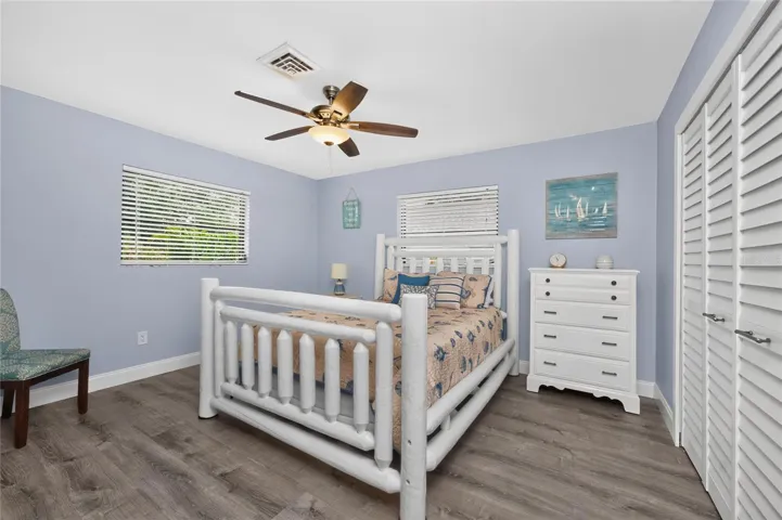 The guest bedroom features vinyl plank flooring and a ceiling fan.