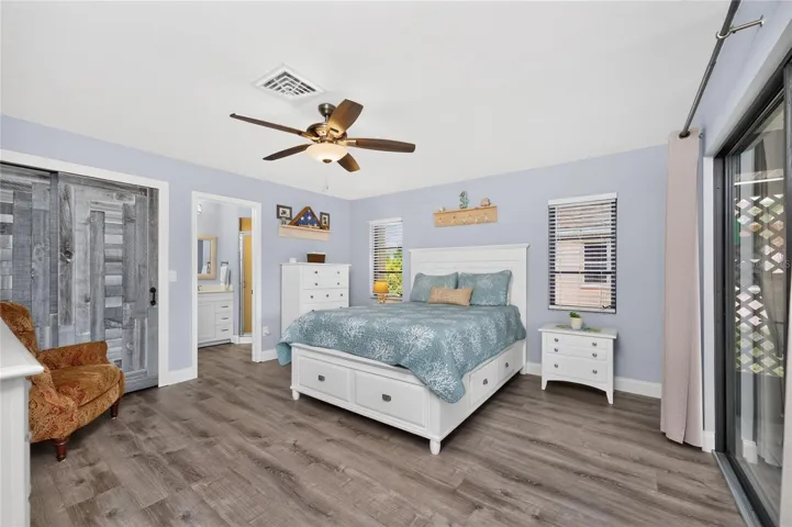 The primary bedroom features  vinyl plank flooring, a ceiling fan and walk-in closet.
