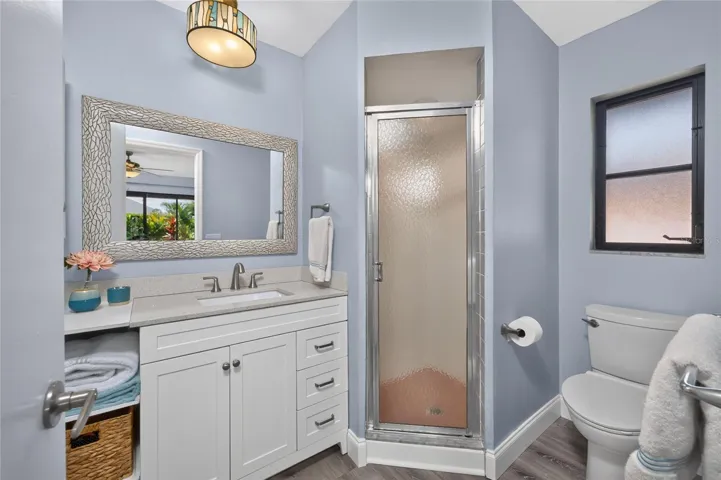 The updated primary bathroom features a solid surface vanity, new mirror, lighting and a shower.