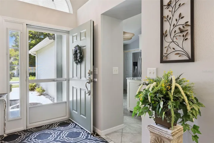 Welcoming entry with high ceilings, arched transom window, tile flooring, and natural light.