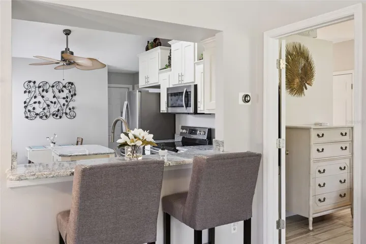 Granite breakfast bar overlooking the updated kitchen with stainless steel appliances, center island, and a bright breakfast nook.