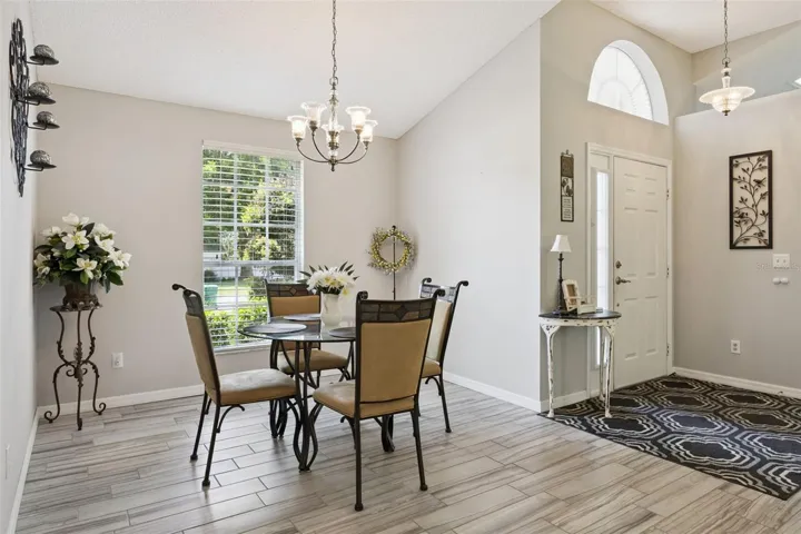 Formal dining space near the front entry with vaulted ceiling, large window, and updated tile flooring.