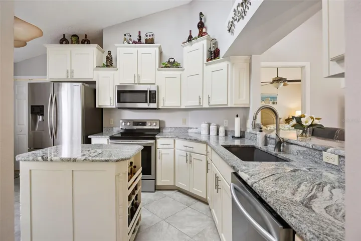 Updated kitchen with granite counters, center island, stainless steel appliances, tile flooring, and a functional layout for cooking and entertaining.