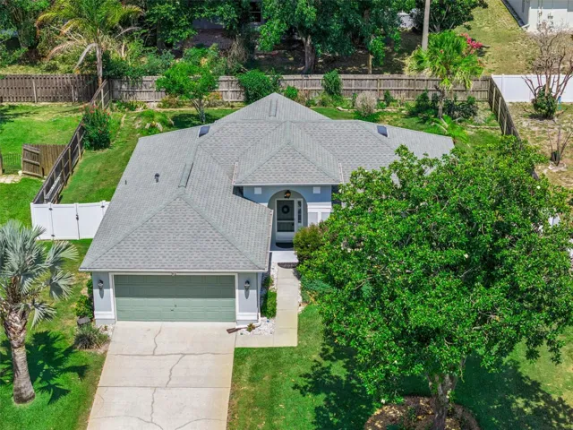 Elevated front view of this Eustis home showing the roofline, front yard, extended driveway, 2 car garage, and fenced side yard.