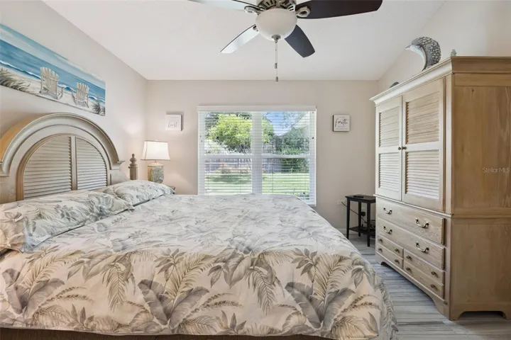 Comfortable primary suite with natural light, updated flooring, ceiling fan, and private access to the en suite bathroom.