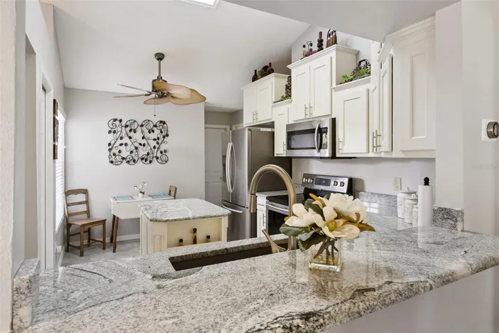 Updated kitchen with granite countertops, center island, stainless steel appliances, pantry storage, and a cozy breakfast nook.