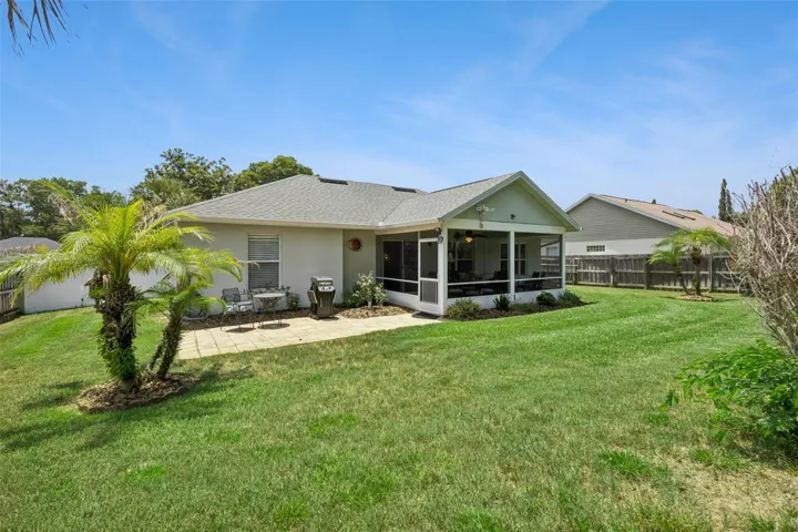 Rear exterior view showing the screened patio, paver patio, fenced backyard, and well maintained lawn.
