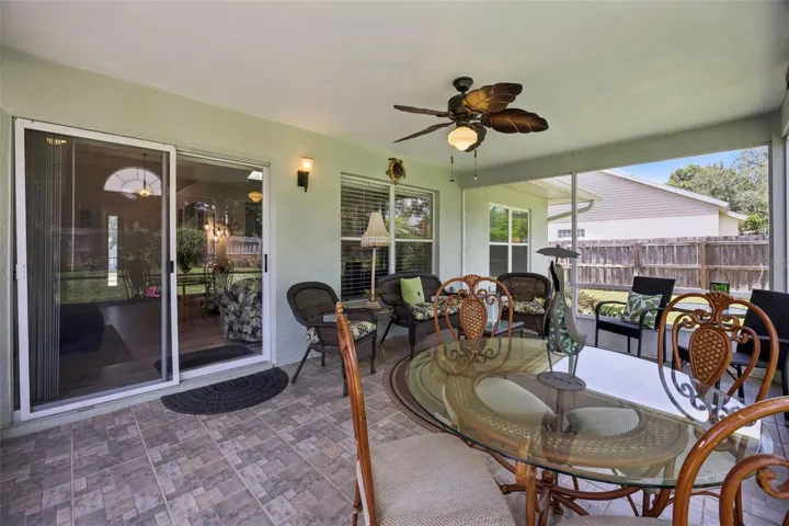 Large screened back patio with dining space, seating area, ceiling fan, and views of the private fenced backyard.