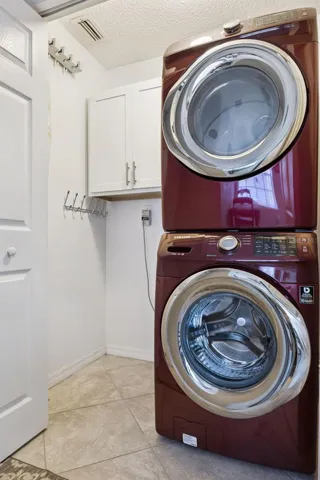 Interior laundry room with cabinetry, hanging storage, and tile flooring.