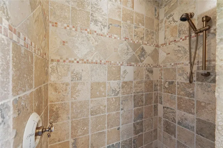 Hand-set stone and intricate mosaic accents bring warmth and character to this walk-in shower, evoking the feeling of a centuries-old European hideaway. Every detail invites you to linger just a little longer beneath the water.