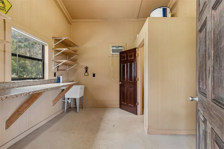 Feed room with utility sink, hot water heater, and toilet