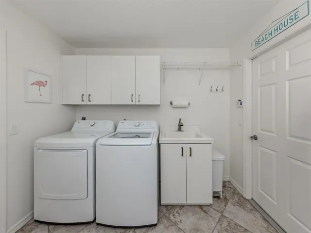 The oversized laundry room includes extra cabinetry, built in desk with storage, utility sink, and leads directly to the garage.